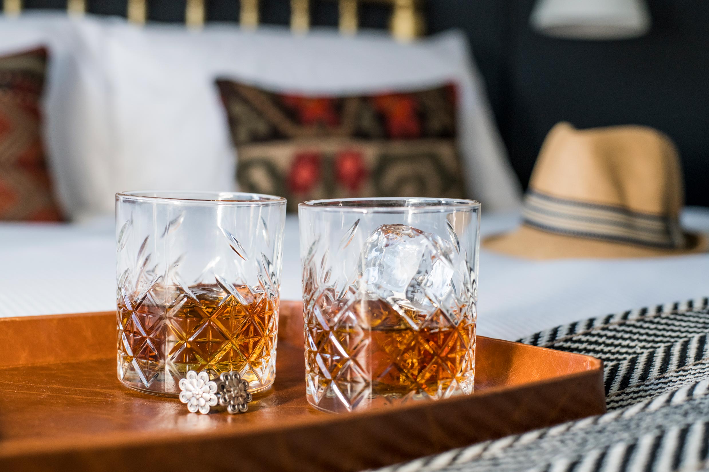 Glasses of Whiskey and Cufflinks on a Bed 