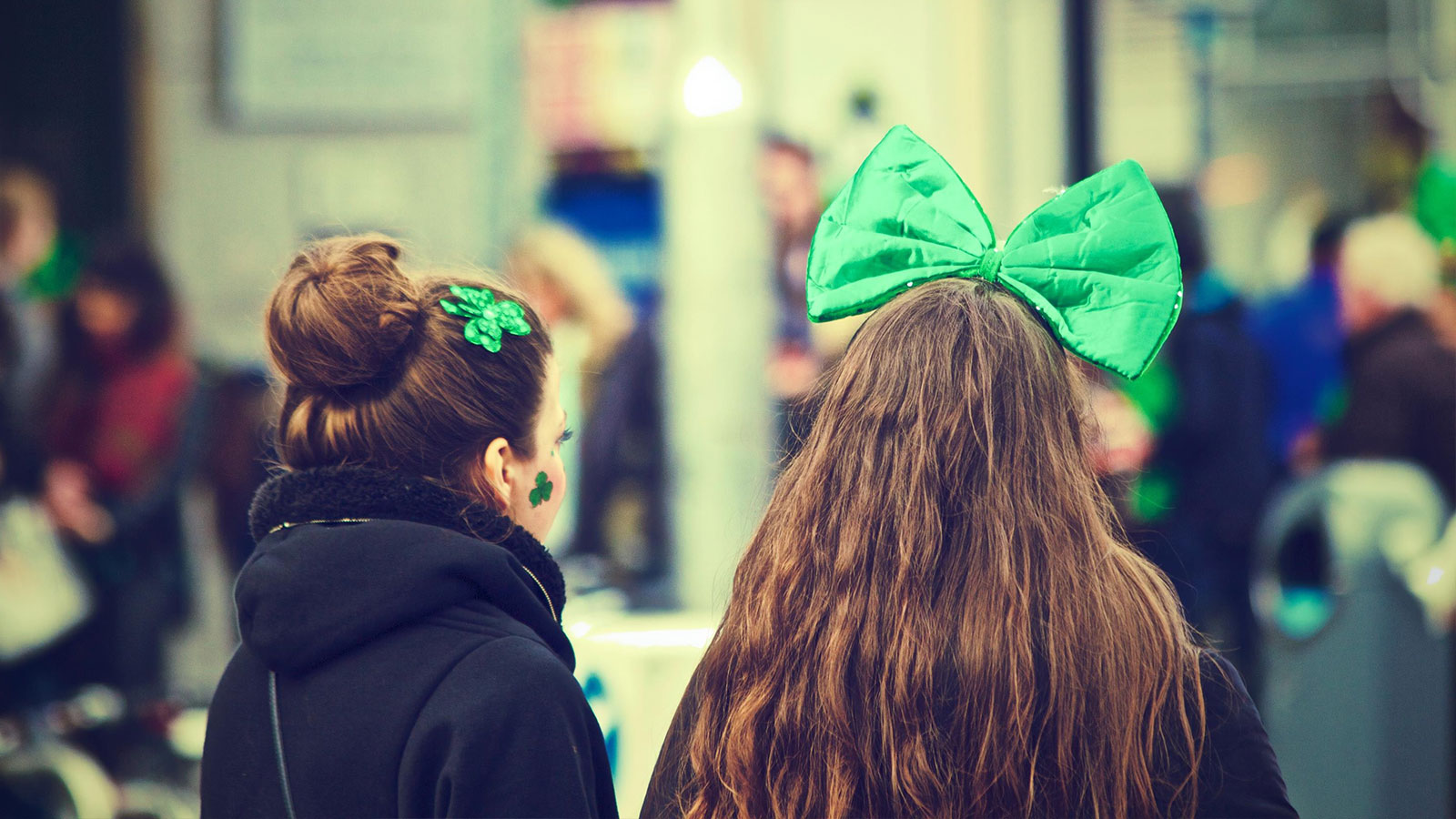Two females, one with large green bow in hair and one with shamrock barrette and shamrock tattoo on her cheek